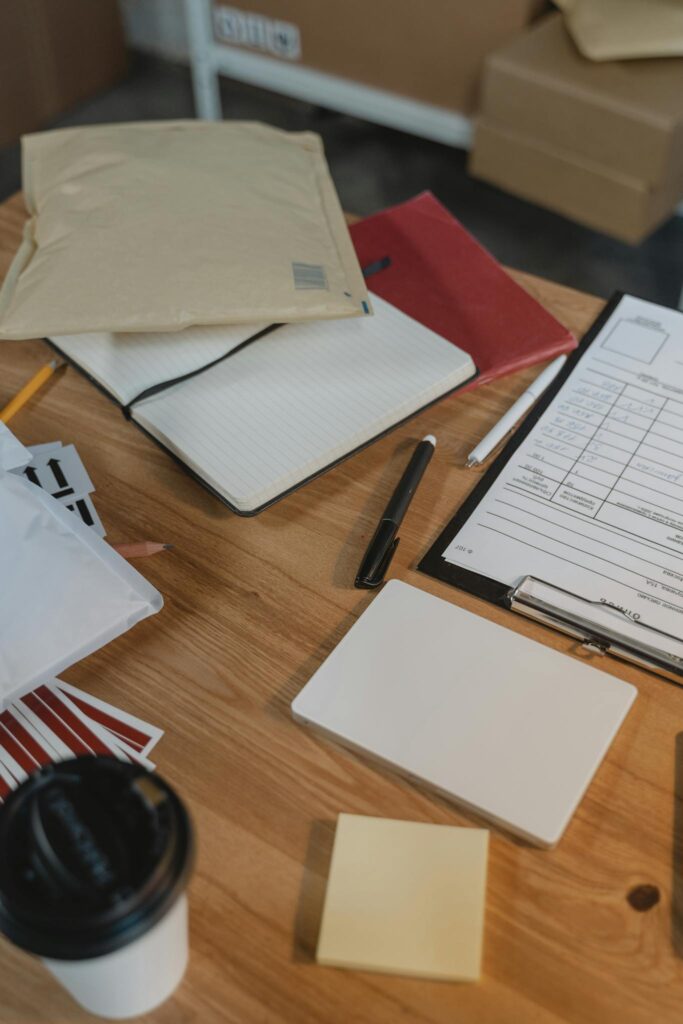 Photo by Tima Miroshnichenko A well-organized desk with delivery packages, clipboard and coffee.